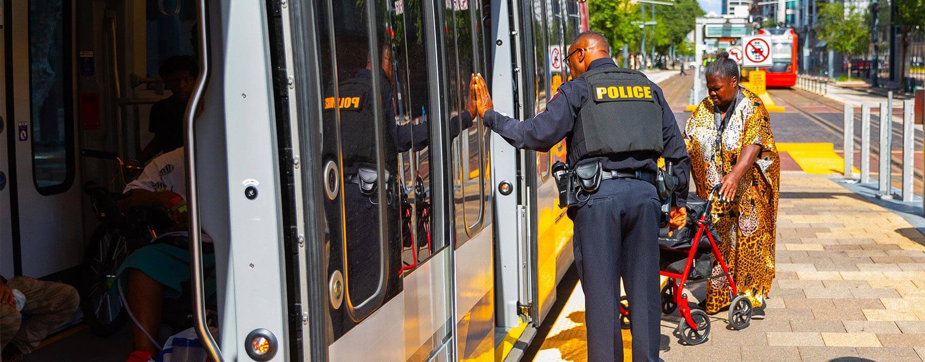 Rider with walker boarding rail at the same time as a Police Officer.